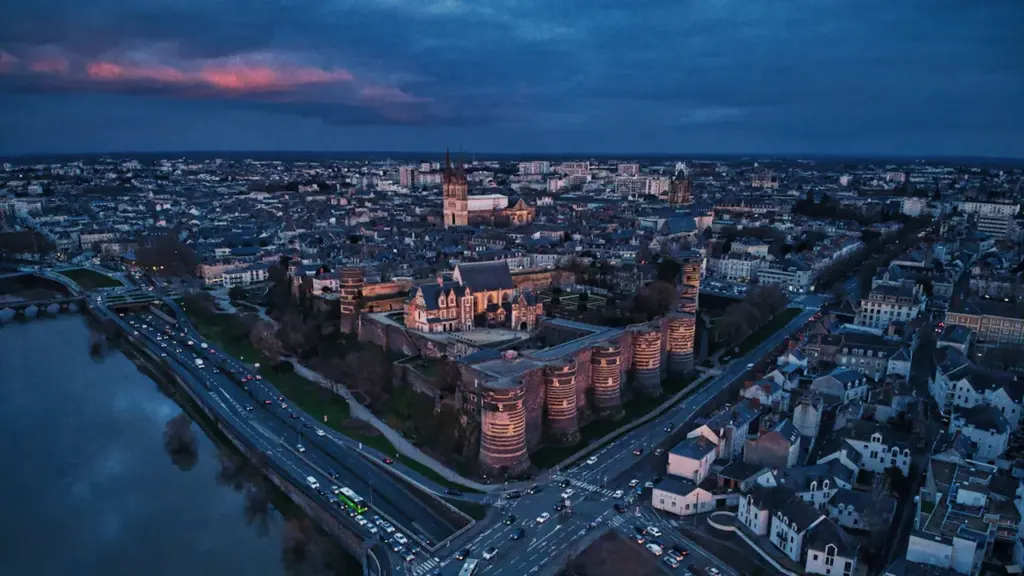 Vue aérienne nocturne du château d'Angers illuminé au-dessus de la Maine.