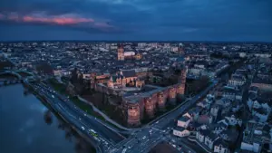 Vue aérienne nocturne du château d'Angers illuminé au-dessus de la Maine.