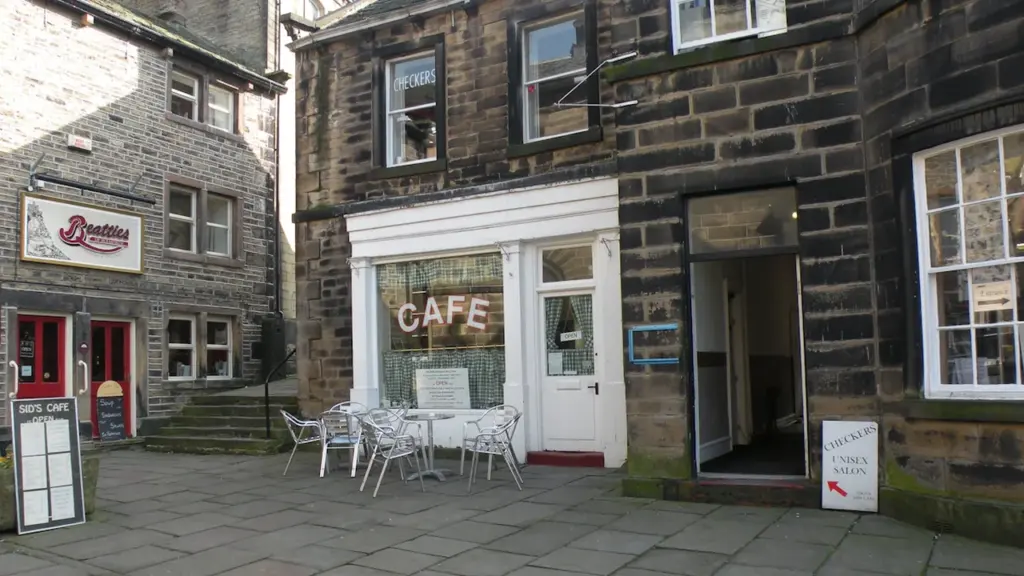 Façade d'un café avec des tables en terrasse dans une rue pavée accueillante.