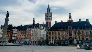 Vue d'ensemble d'une grande place historique lilloise avec des bâtiments et un monument central.