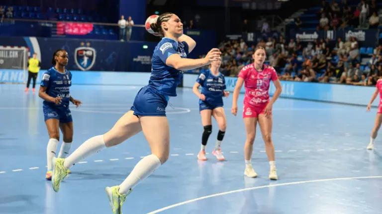 Une joueuse de handball en plein saut s'apprête à tirer au but en plein match.