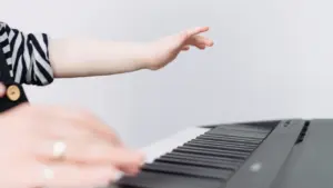 Les mains d'un enfant apprenant à jouer du piano sur un clavier.