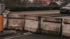 Voiture noire roulant sur une rue près de barrières de sécurité en béton.