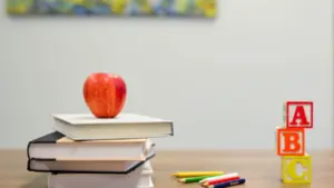 Une pomme rouge posée sur des livres scolaires avec des cubes ABC en bois.