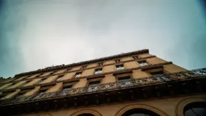 Façade d'un bâtiment administratif en béton sous un ciel nuageux en journée.