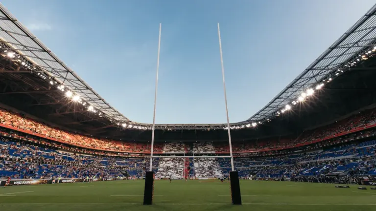 Vue impressionnante d'un grand stade de rugby vide sous un ciel dégagé.