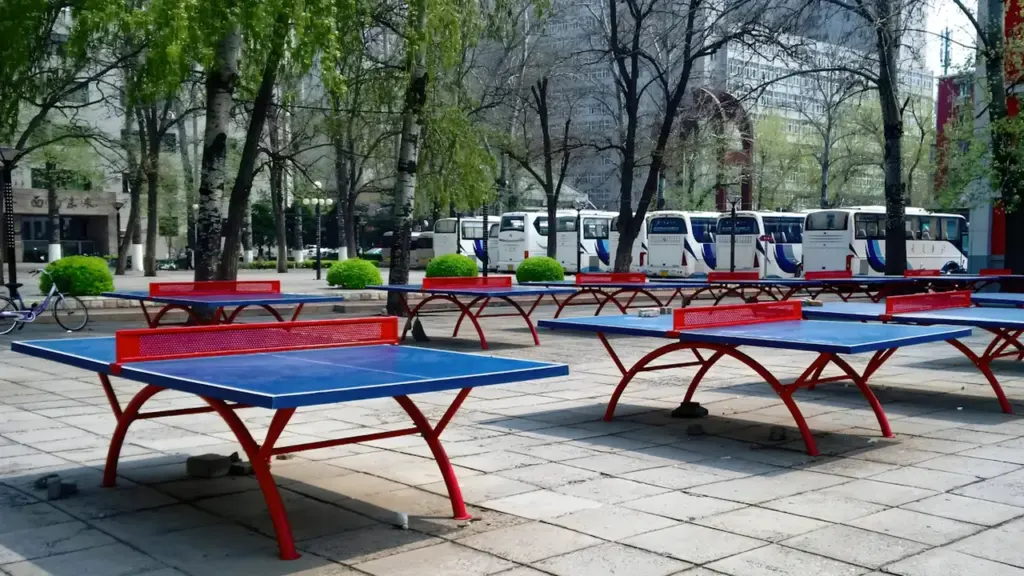 Tables de ping-pong en plein air dans un parc public urbain arboré.