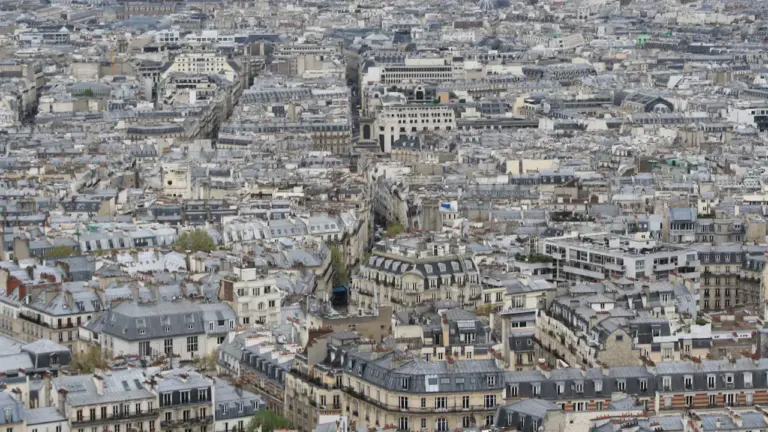 Vue aérienne étendue des toits et immeubles caractéristiques d'une ville française dense.