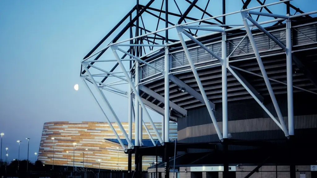 Vue architecturale moderne d'un complexe sportif urbain sous une lumière crépusculaire.