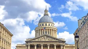 Vue emblématique du Panthéon à Paris avec le drapeau français sous un ciel ensoleillé.