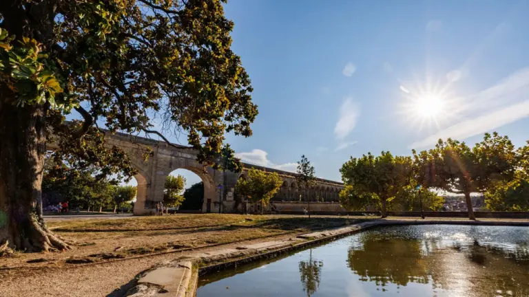 Vaste aqueduc en pierre dominant un étang sous un ciel bleu ensoleillé en France.