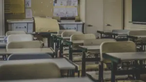 Une salle de classe vide avec des petites tables et des chaises pour enfants.