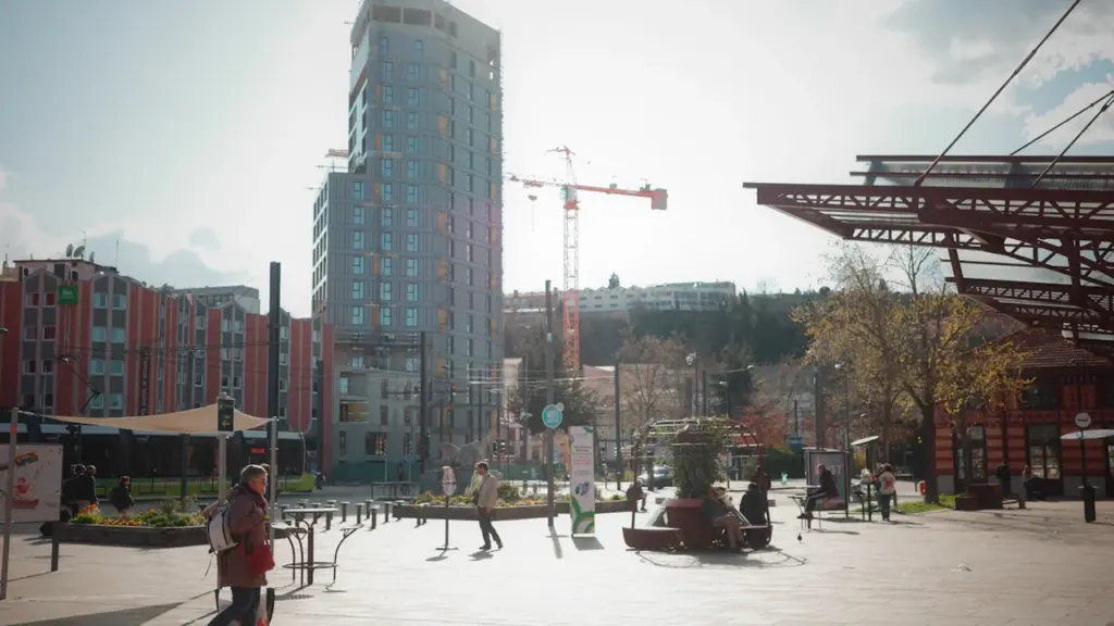 Une place urbaine animée à Saint-Étienne avec des piétons et des bâtiments modernes.