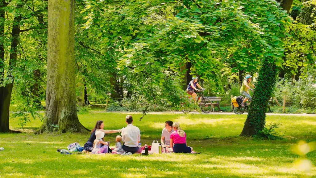 Une famille profite d'un pique-nique dans un parc verdoyant et ensoleillé en ville.