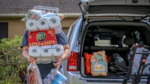 Une personne chargeant des provisions et des produits essentiels dans un coffre de voiture.