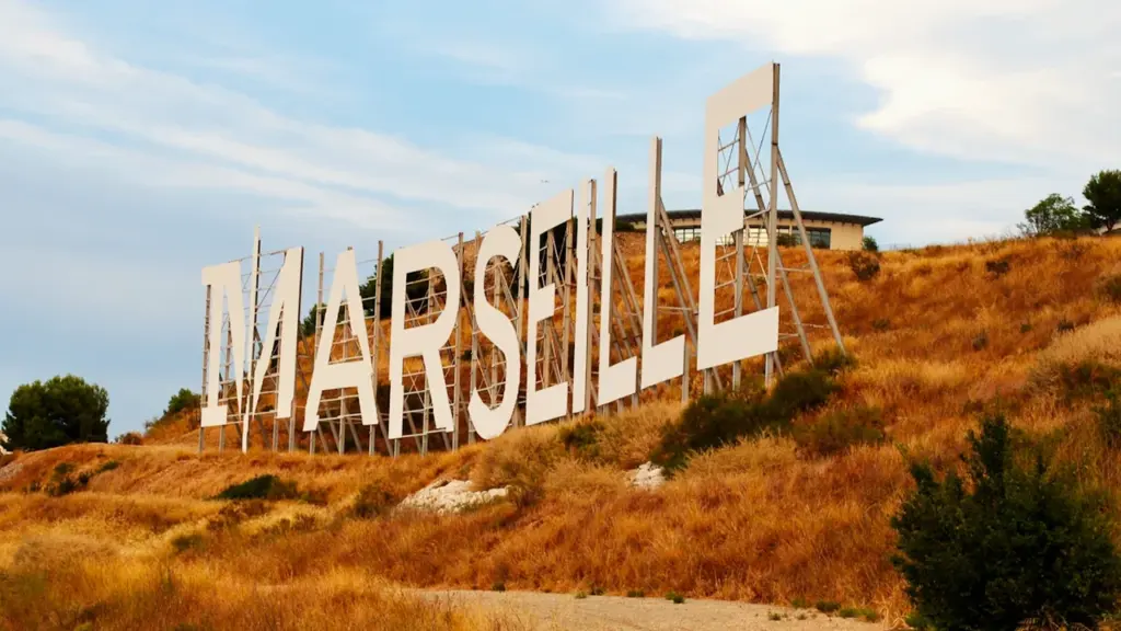 Le panneau monumental Marseille installé sur une colline sous un ciel bleu dégagé.