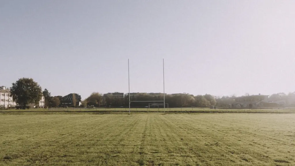 Vue d'un terrain de rugby avec ses poteaux sous un ciel dégagé.