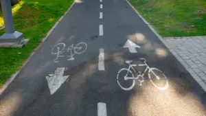 Marquage au sol d'une piste cyclable avec des flèches blanches directionnelles.