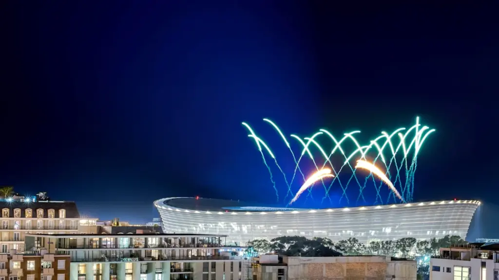 Feu d'artifice spectaculaire illuminant le ciel nocturne au-dessus d'un bâtiment moderne urbain.