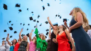 Un groupe de diplômés lançant joyeusement leurs mortiers dans un ciel bleu dégagé.