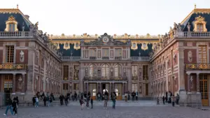 Vue d'ensemble du château de Versailles avec des visiteurs sur la place principale.