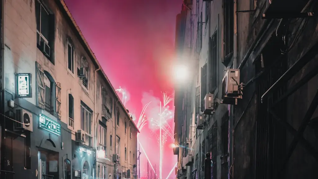 Feu d'artifice illuminant une rue étroite au cœur de Marseille lors des festivités estivales.