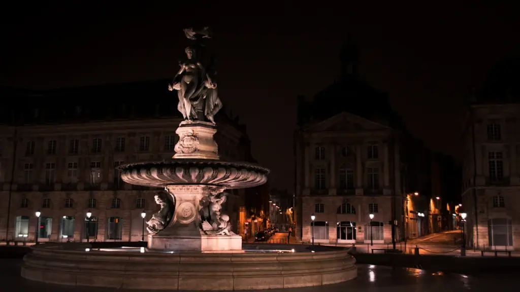 Fontaine en pierre blanche traditionnelle sur une place publique en France.