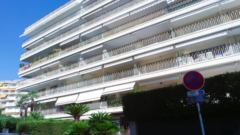 Immeuble résidentiel typique à Cannes avec balcons et végétation méditerranéenne ensoleillée