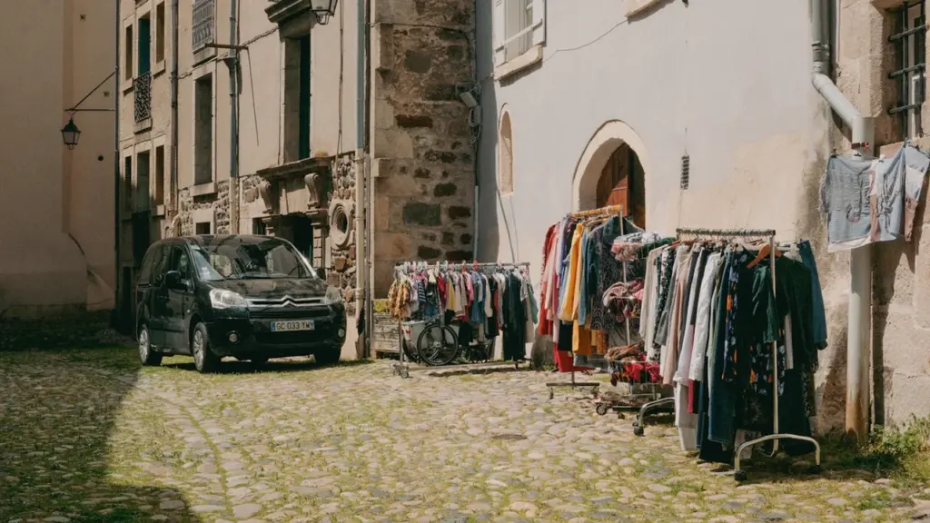 Racks de vêtements disposés sur une place pavée historique dans une ville française.