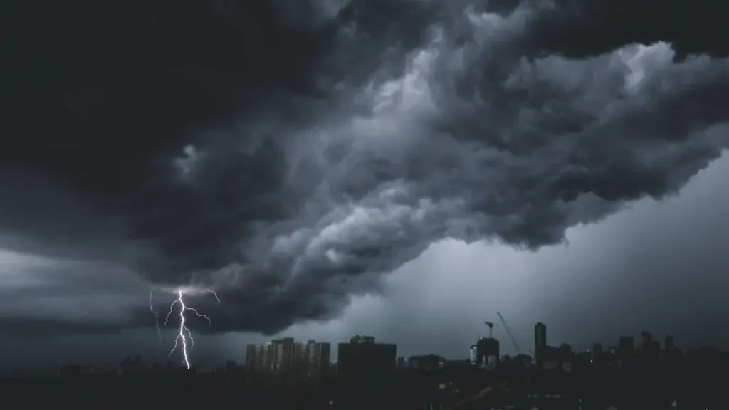 Un violent orage s'approche d'une zone urbaine avec des éclairs frappant le ciel.