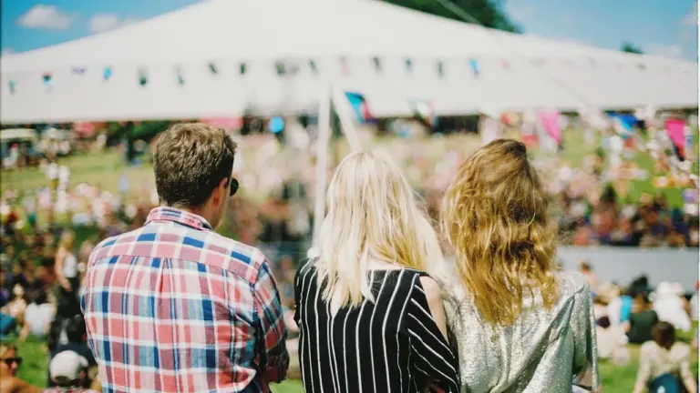Trois jeunes personnes profitent d'un événement festif en plein air sous un grand chapiteau.