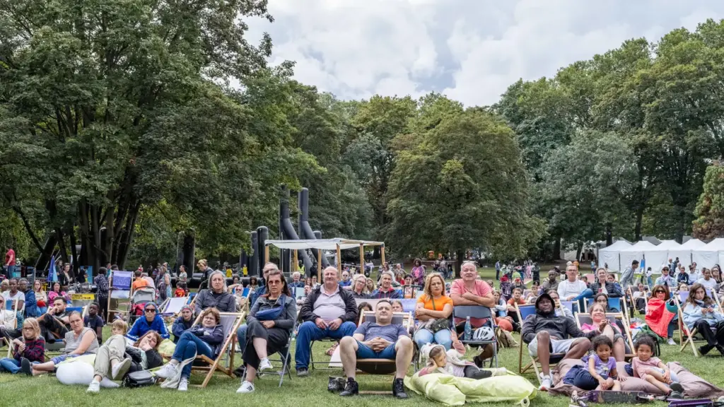 Un groupe de personnes assises sur des chaises longues dans un parc verdoyant et arboré.
