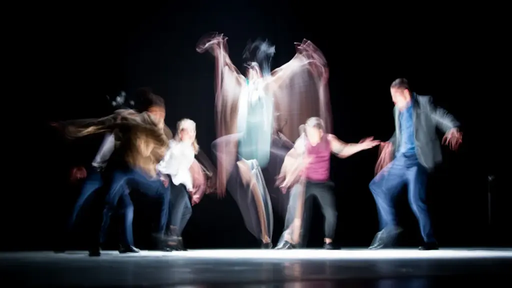 Danseurs sur scène effectuant une performance artistique dynamique dans une ambiance sombre