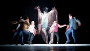 Danseurs sur scène effectuant une performance artistique dynamique dans une ambiance sombre