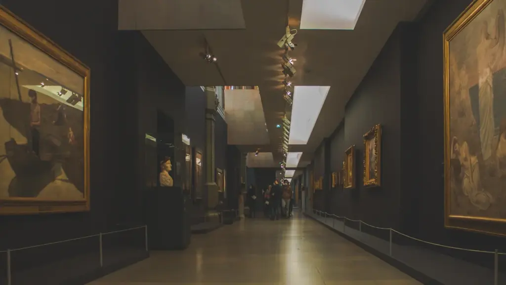 Intérieur d'un musée français avec des peintures classiques exposées sur un long mur.
