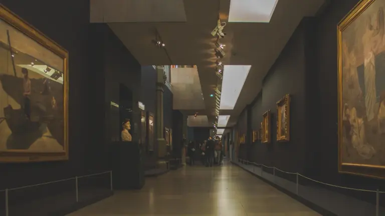 Intérieur d'un musée français avec des peintures classiques exposées sur un long mur.