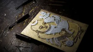 Gros plan sur une plaque de gravure artistique posée sur un établi en bois.