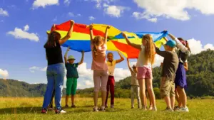 Groupe d'enfants jouant avec un parachute multicolore dans un parc verdoyant.