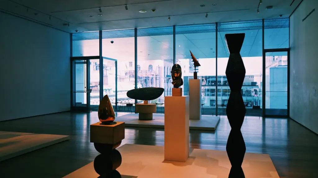 Une galerie d'art contemporain lumineuse avec des sculptures sur des socles en bois.