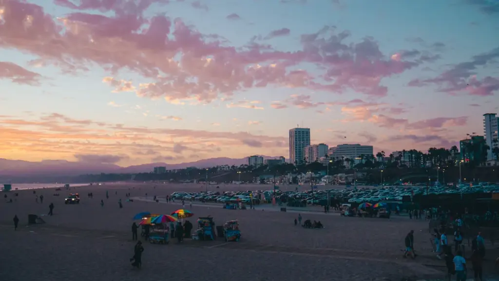 Coucher de soleil coloré sur une plage urbaine avec des bâtiments en arrière-plan.