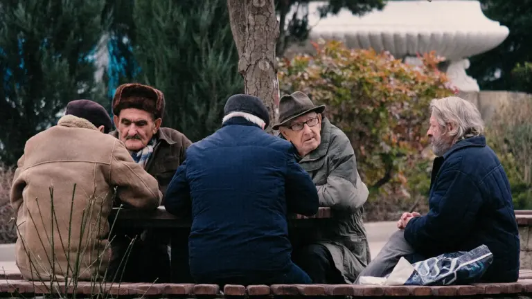 Un groupe de seniors discutant autour d'une table dans un parc public à Montélimar.