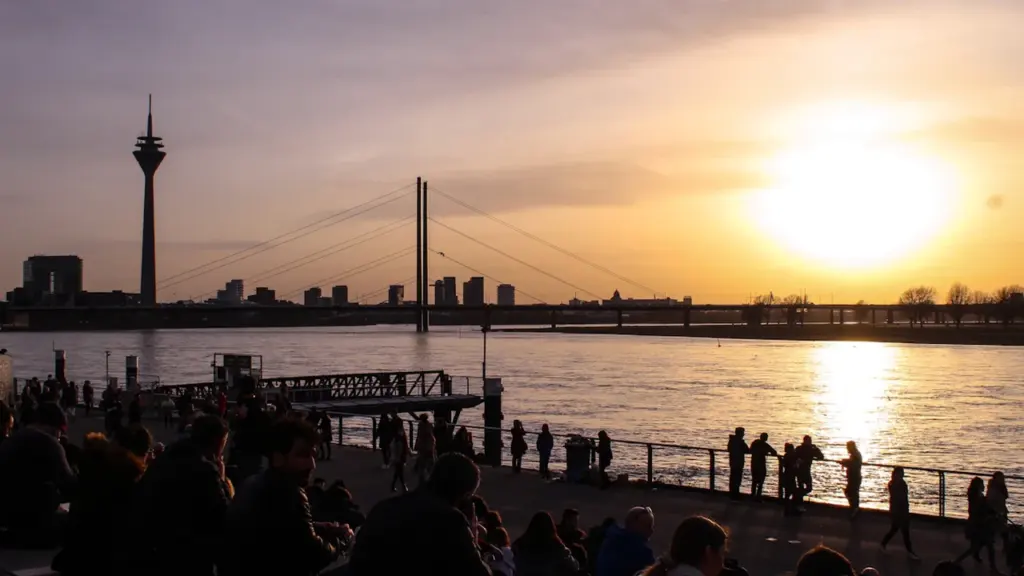 Silhouette de personnes profitant du coucher de soleil au bord d'une rivière animée.