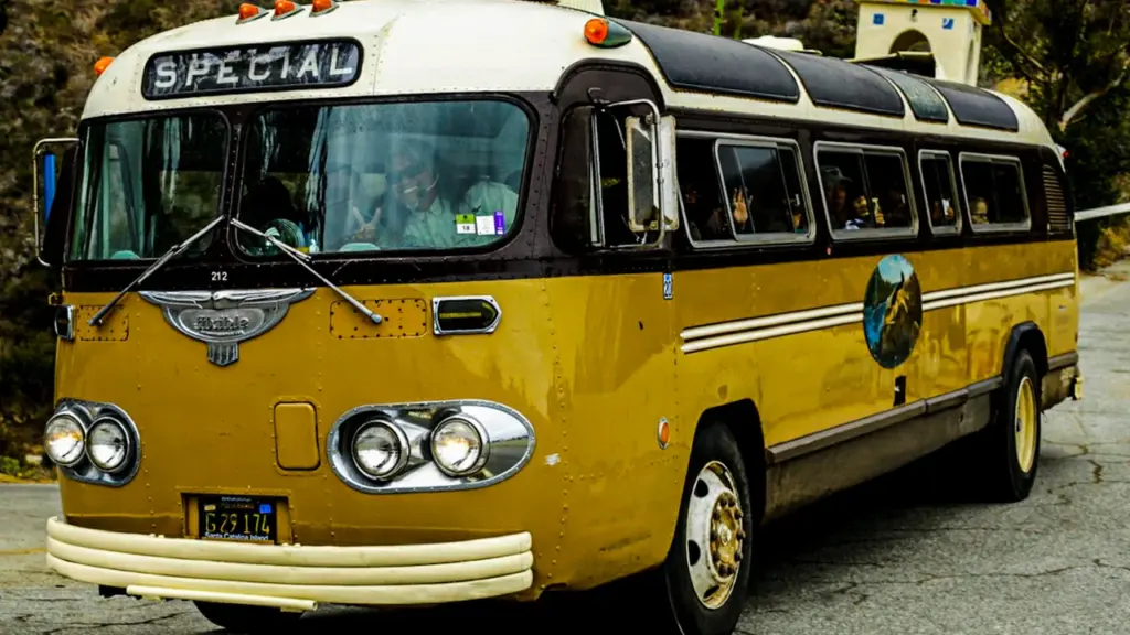 Un autocar vintage jaune circulant sur une route pour assurer les navettes locales.