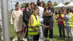Un groupe de jeunes enfants et adolescents sur un terrain de sport en extérieur.