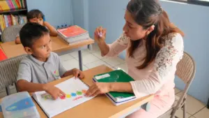 Une enseignante accompagne un jeune élève durant une activité pédagogique dans une salle de classe.