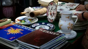 Une sélection de vaisselle de prestige et magazines sur une table de chineur.