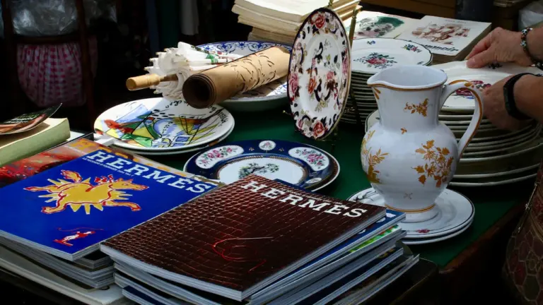 Une sélection de vaisselle de prestige et magazines sur une table de chineur.