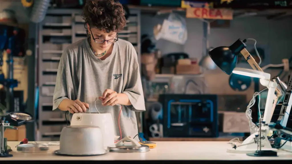 Une jeune femme aux cheveux bouclés répare un appareil électrique avec un multimètre dans l'atelier.